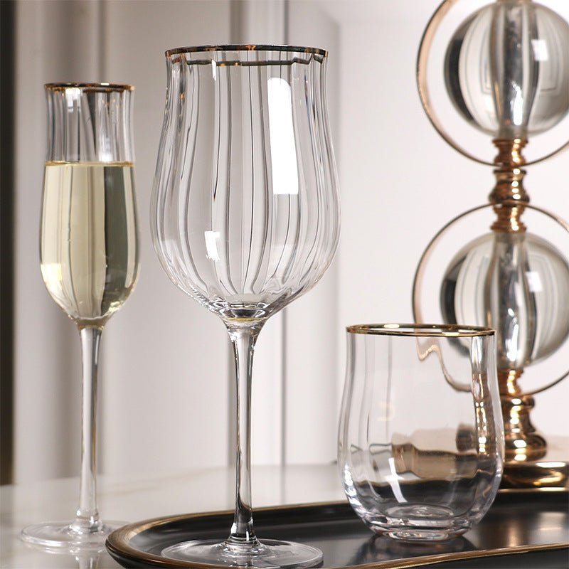 Set of glassware including a flute, wine glass, and bowl on a reflective surface with a neutral background.