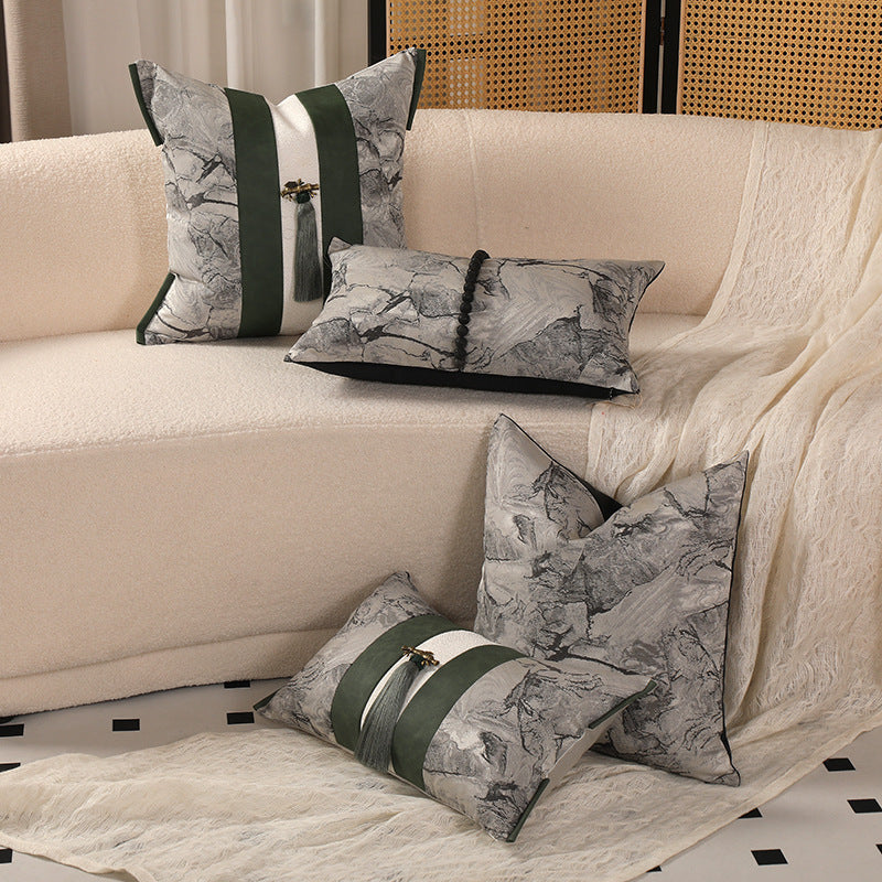 Decorative pillows on a beige sofa with a patterned rug and wooden screen in the background.