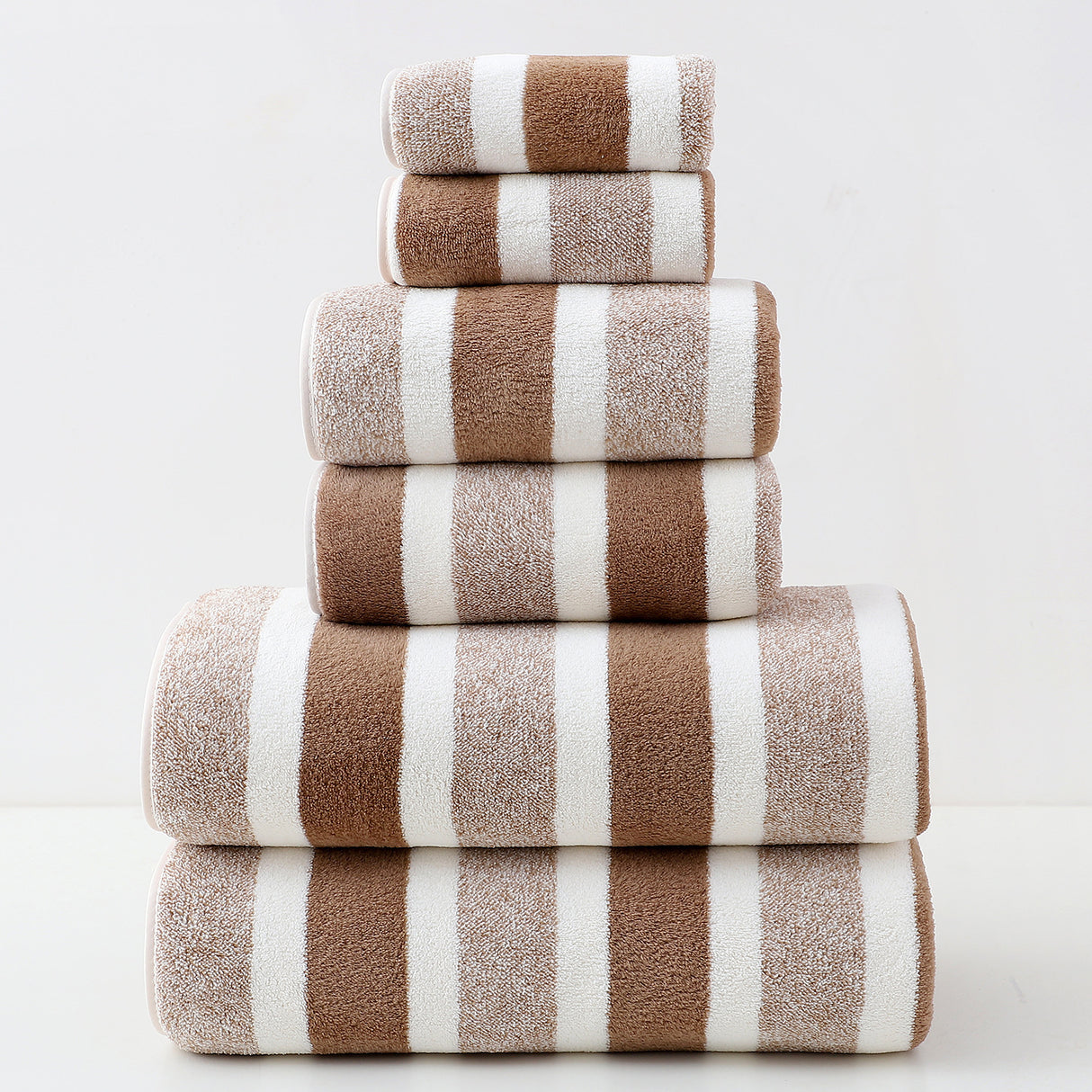 Stack of brown and white striped towels on a light gray background
