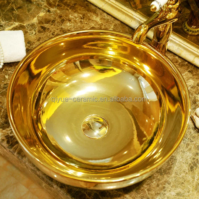 Gold ceramic bowl with handles on a marble surface