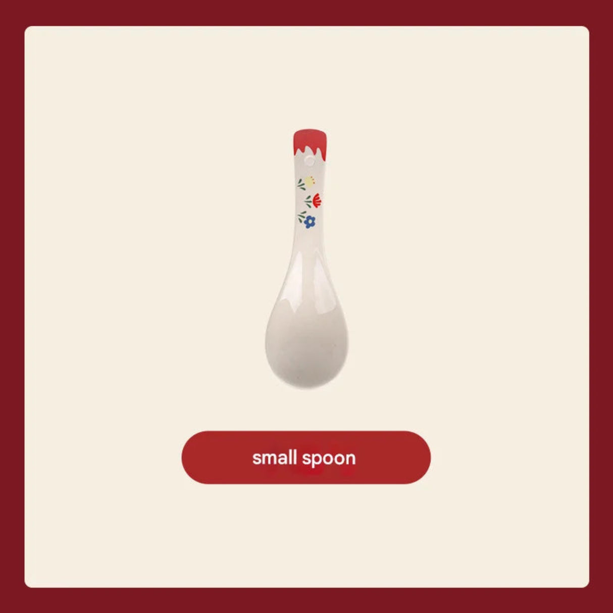 White ceramic spoon with floral design on a red handle against a beige background