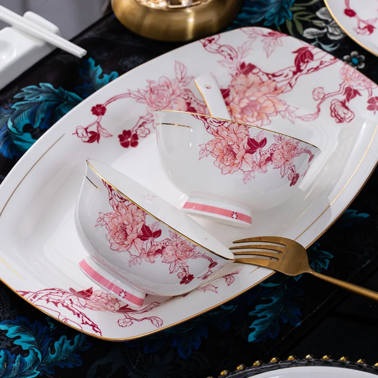 Floral teacup and saucer set on a decorative tablecloth with a fork.