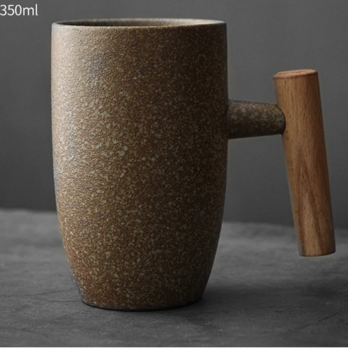 Brown ceramic mug with wooden handle on a gray background