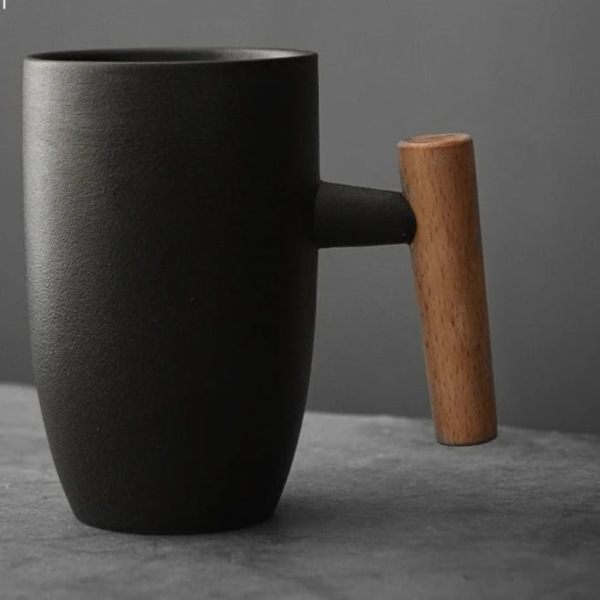 Black mug with a wooden handle on a gray surface