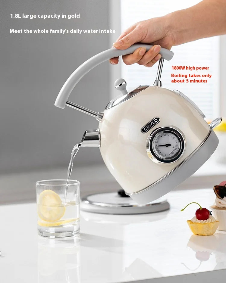White electric kettle being used to pour water into a glass on a kitchen counter.