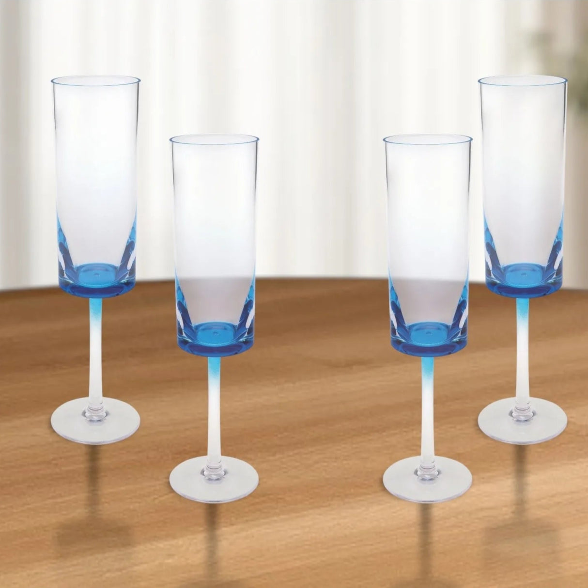 Four champagne flutes with blue accents on a wooden table
