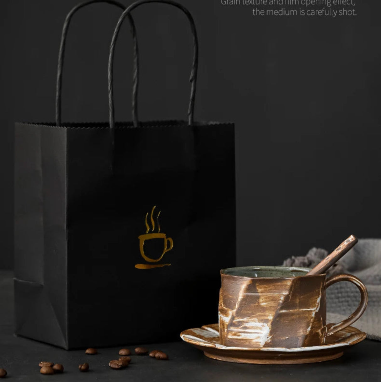 Black paper bag with a coffee cup design, placed on a dark surface with text overlay.