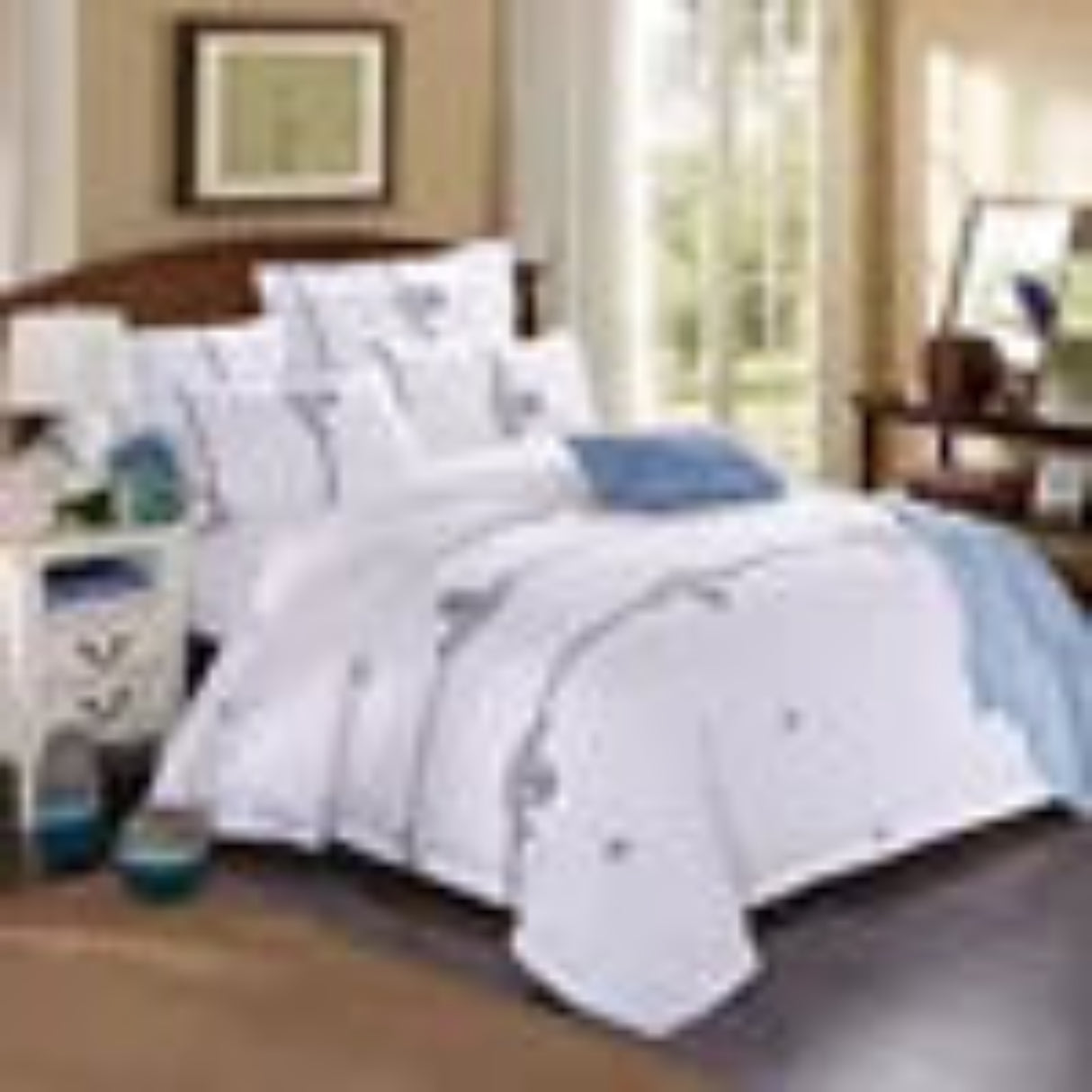 Bedding set with white comforter and blue pillows on a bed in a bedroom setting.