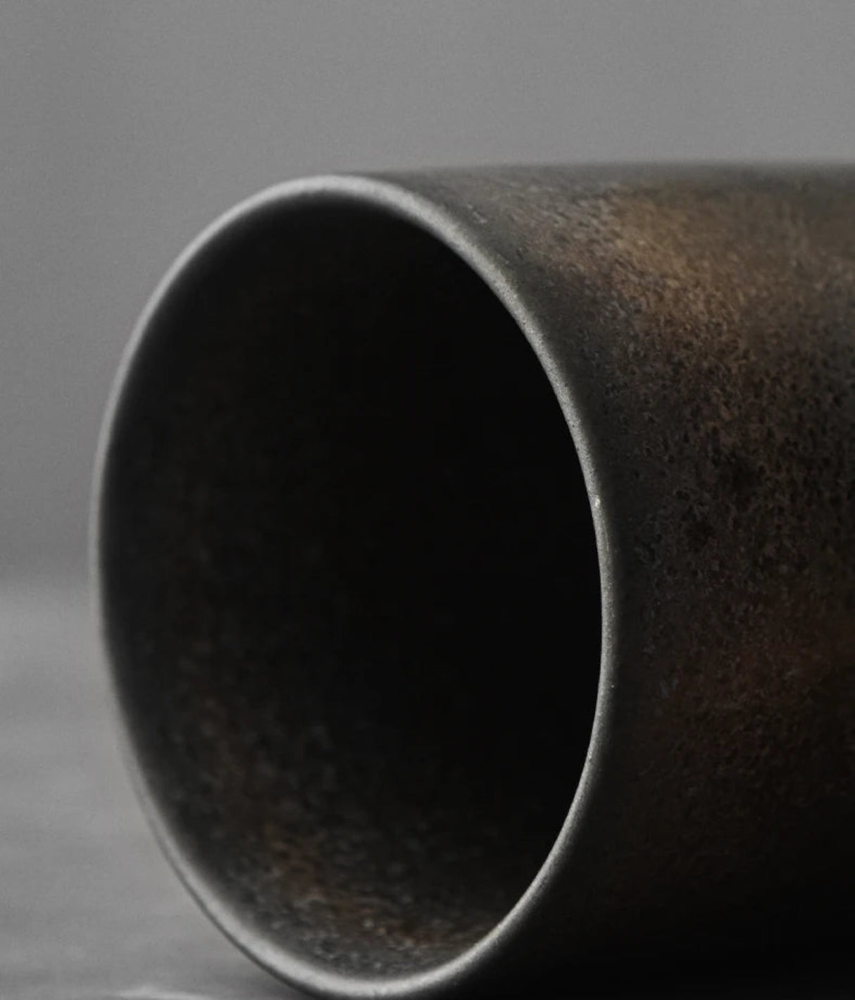 Close-up of a dark ceramic cup on a gray background