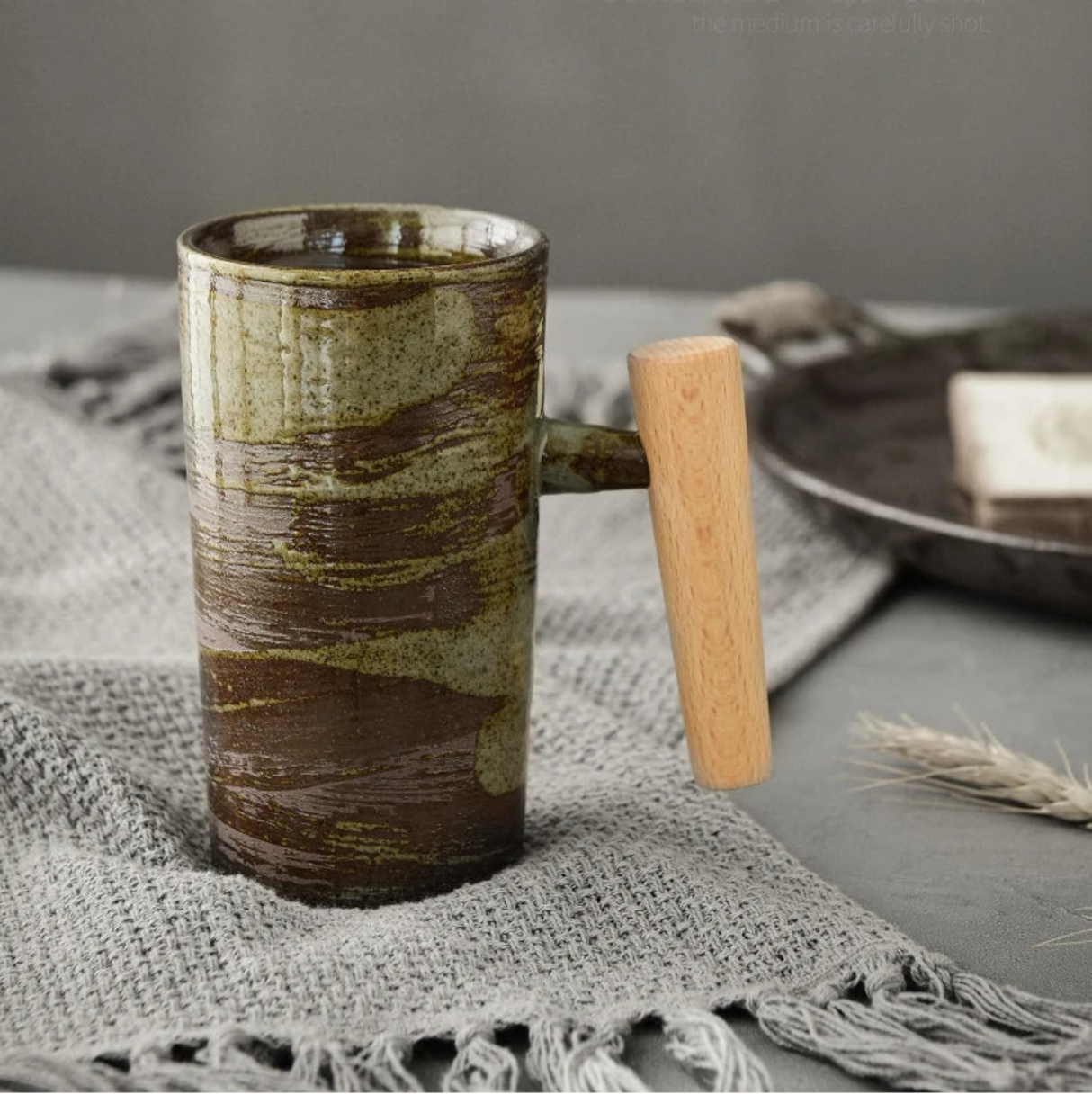 Ceramic mug with wooden handle on a textured surface