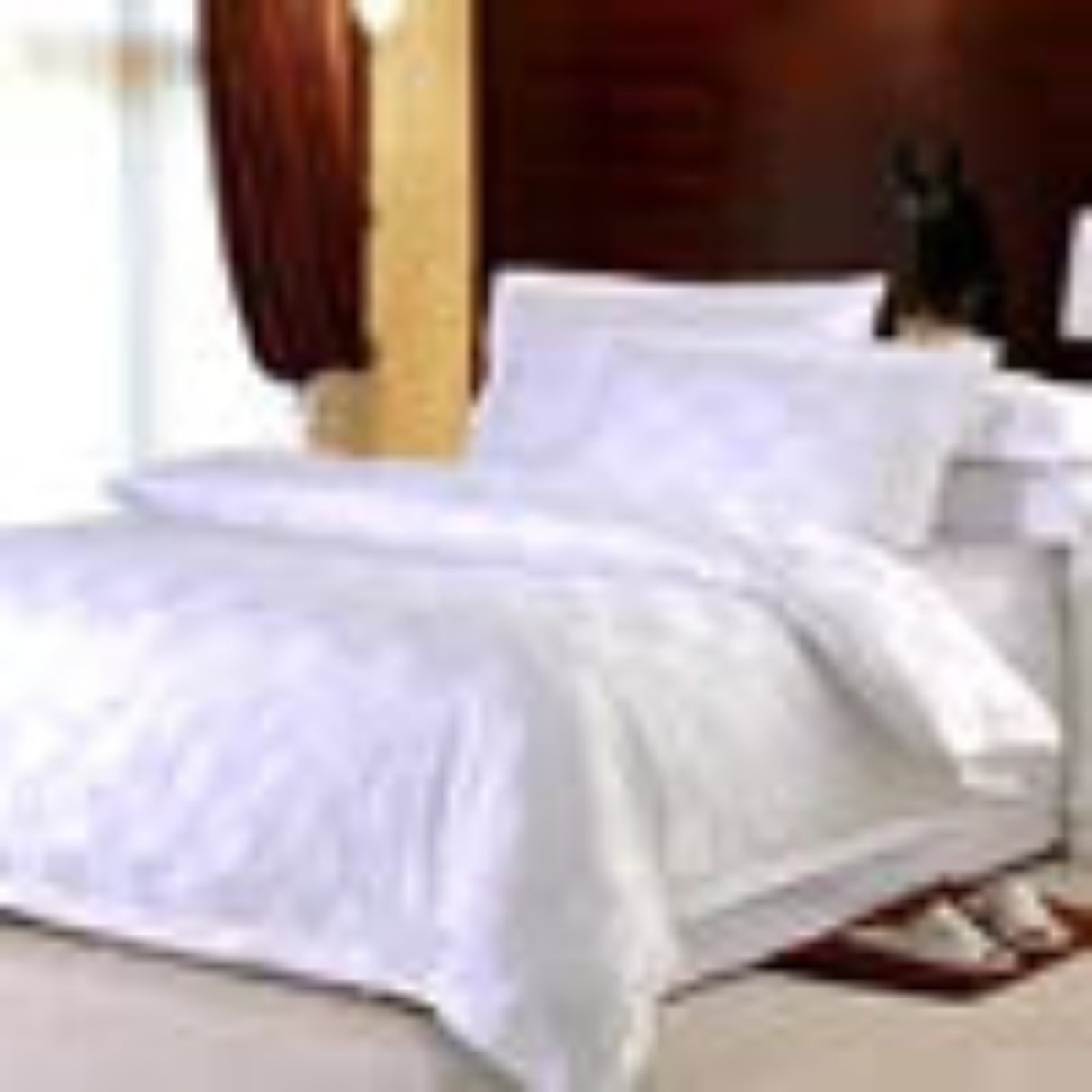 White bed sheets on a bed with pillows and a wooden headboard.