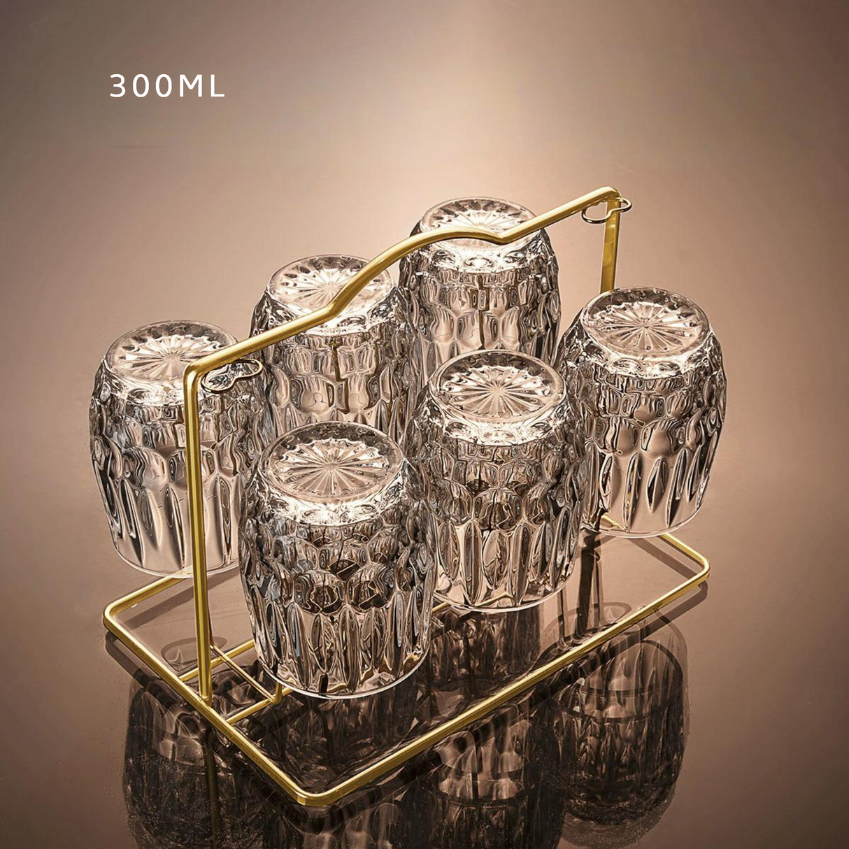 Set of six clear glass tumblers with a gold stand on a reflective surface.