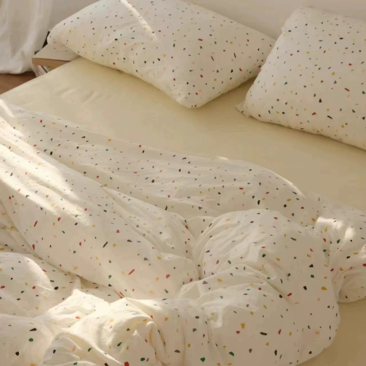 White bedding set with colorful speckles on a bed