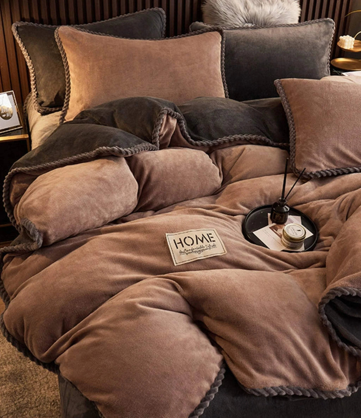 Brown and gray bedding set with 'HOME' label on a bed.