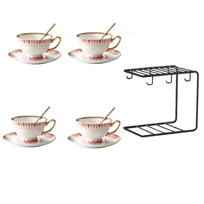 Set of four ceramic tea cups with saucers and a black metal shelf on a white background
