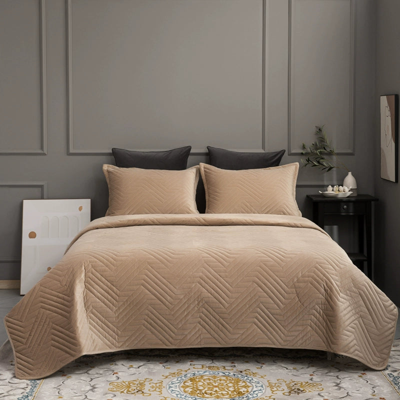 Beige quilted coverlet on a bed with pillows in a bedroom setting.