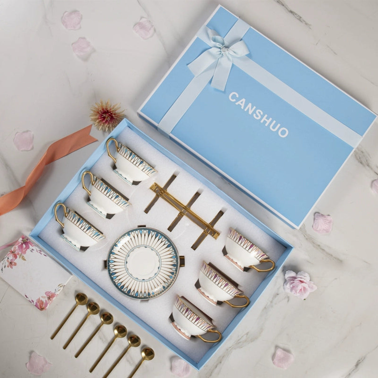 Tea set with decorative elements in a 'CANSHUO' branded box on a marble surface.