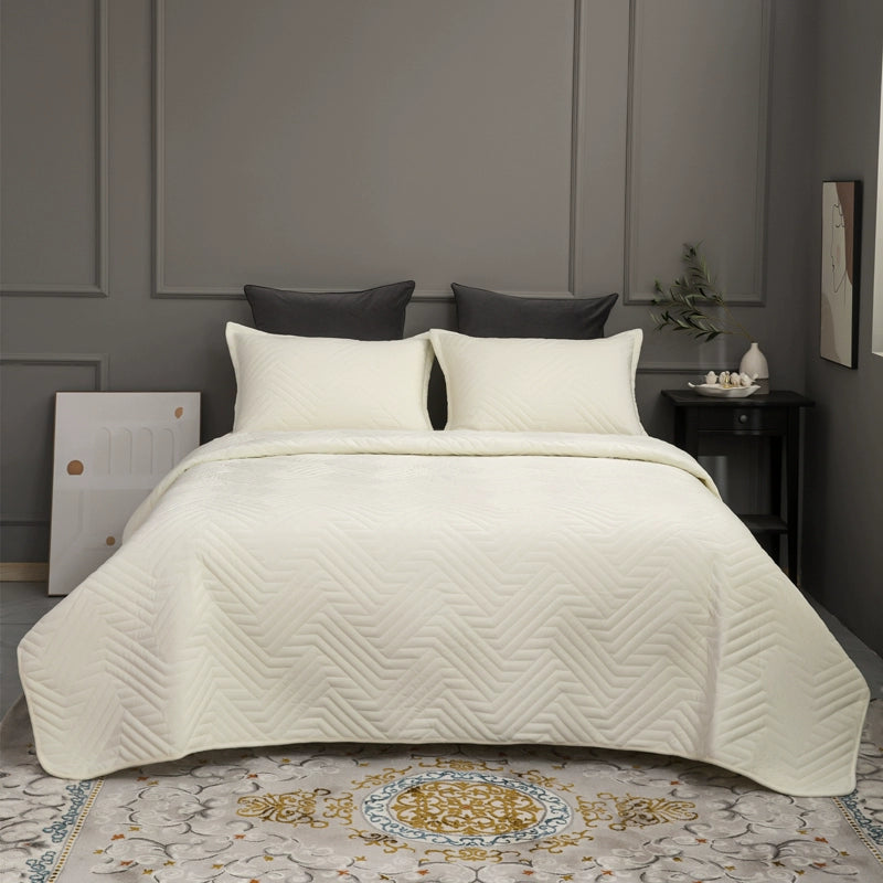 Beige quilt on a bed in a bedroom with dark walls and decorative elements.