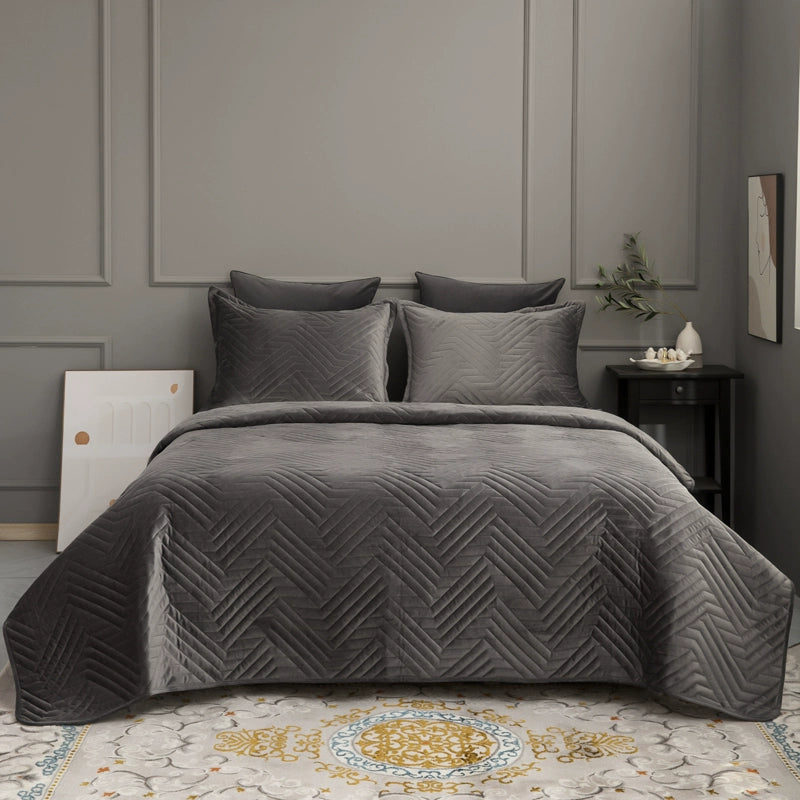 Gray quilt and pillows on a bed in a bedroom setting