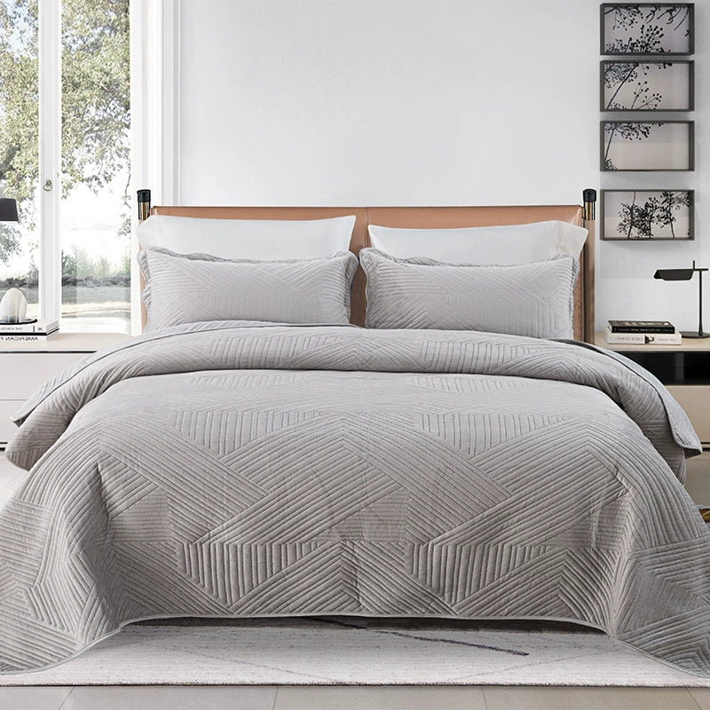 Gray quilt with geometric pattern on a bed in a bedroom setting