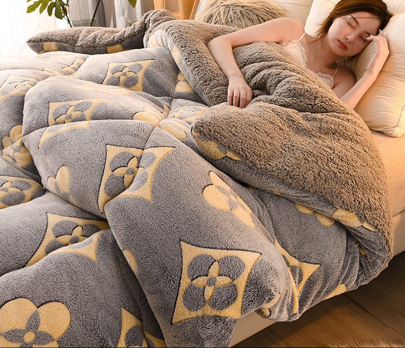 Person lying on a bed with a patterned gray and beige blanket