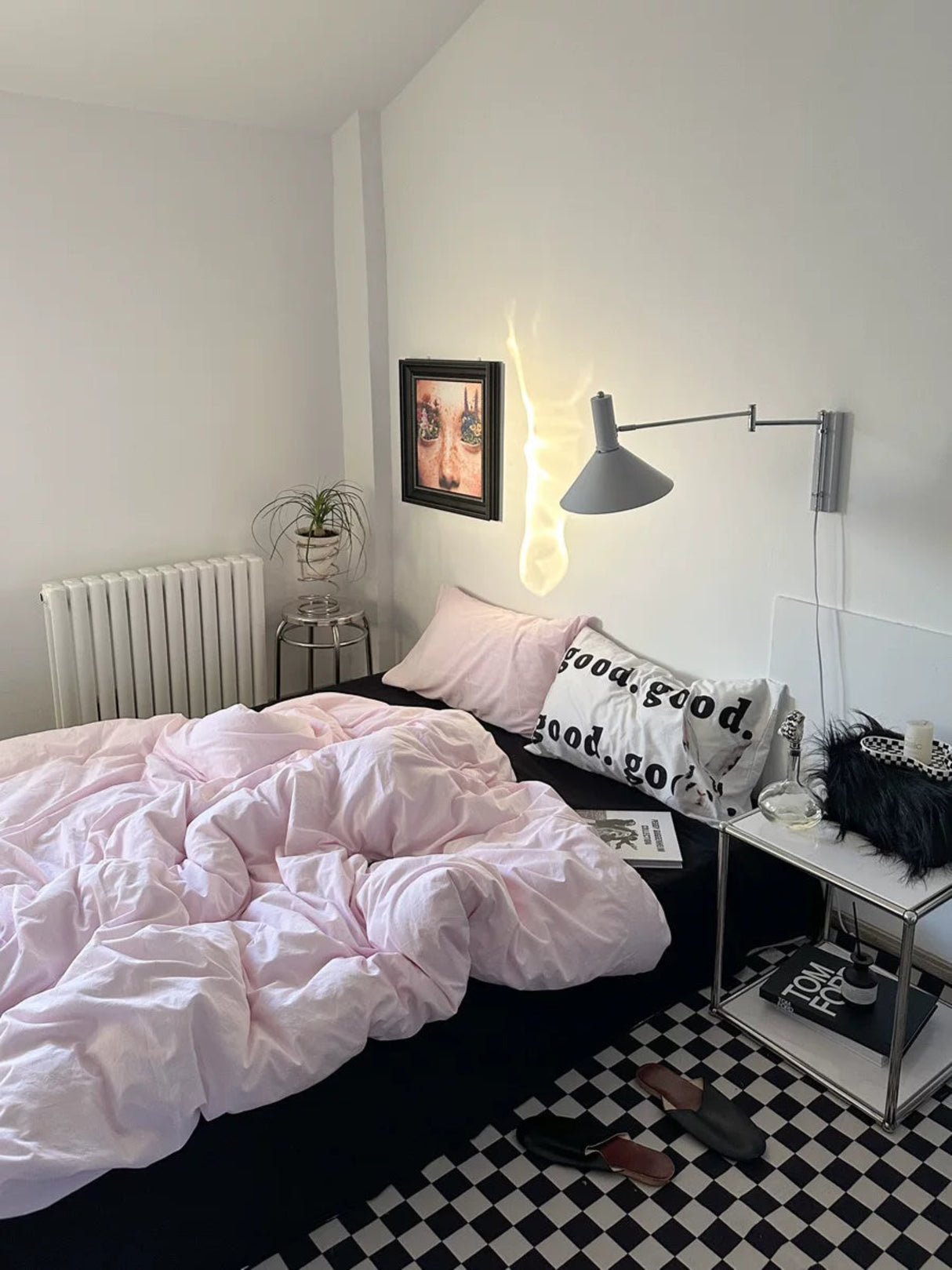 Bedroom with pink bedding, black and white checkered floor, and wall art.