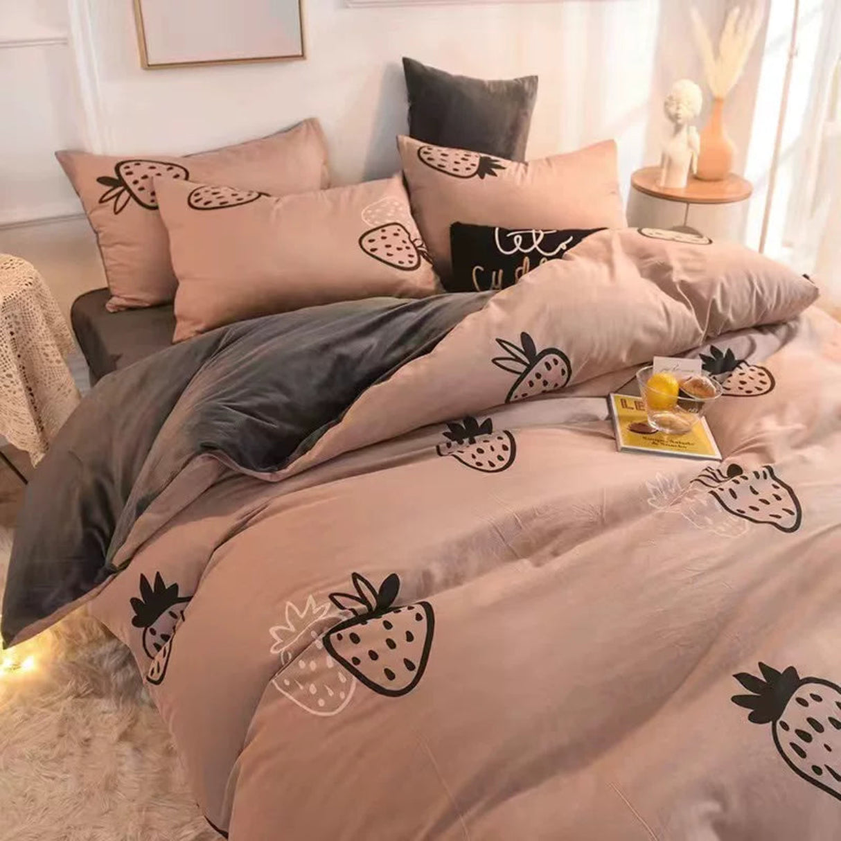 Neatly made bed with strawberry patterned bedding in a bedroom setting.