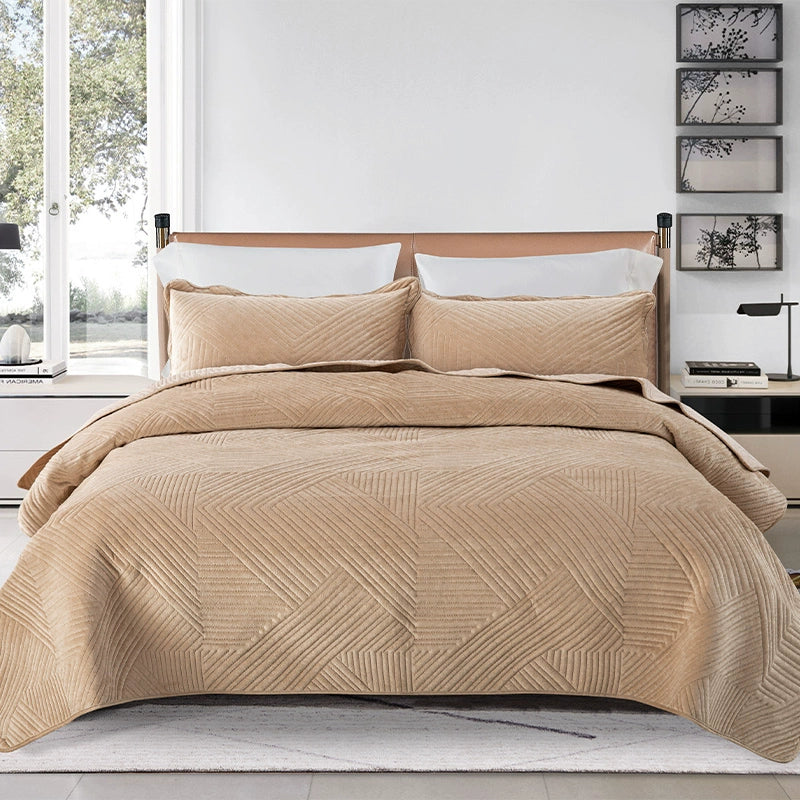 Beige quilted coverlet on a bed with pillows in a bedroom setting.