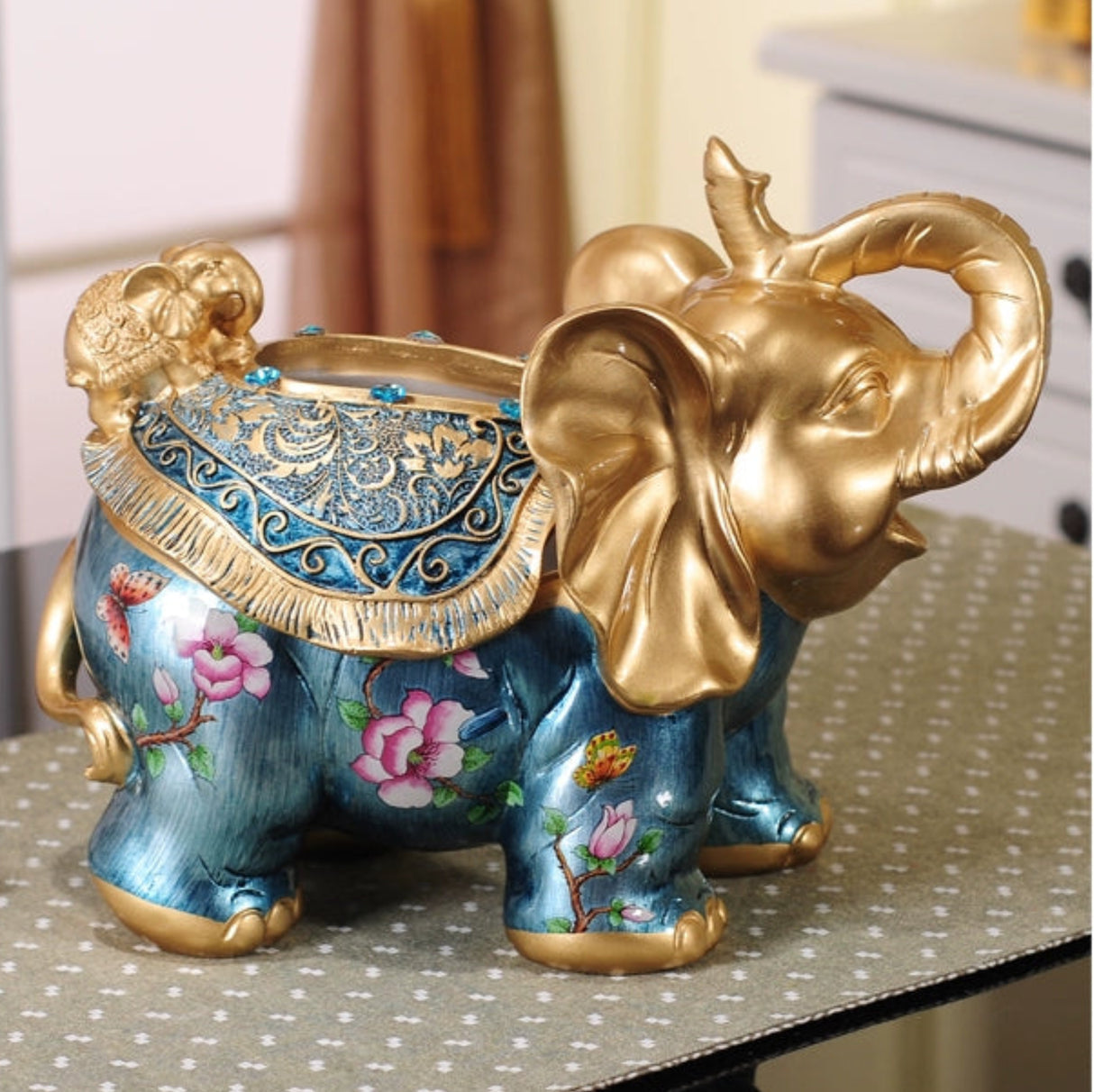 Decorative elephant figurine with gold accents and floral designs on a table.