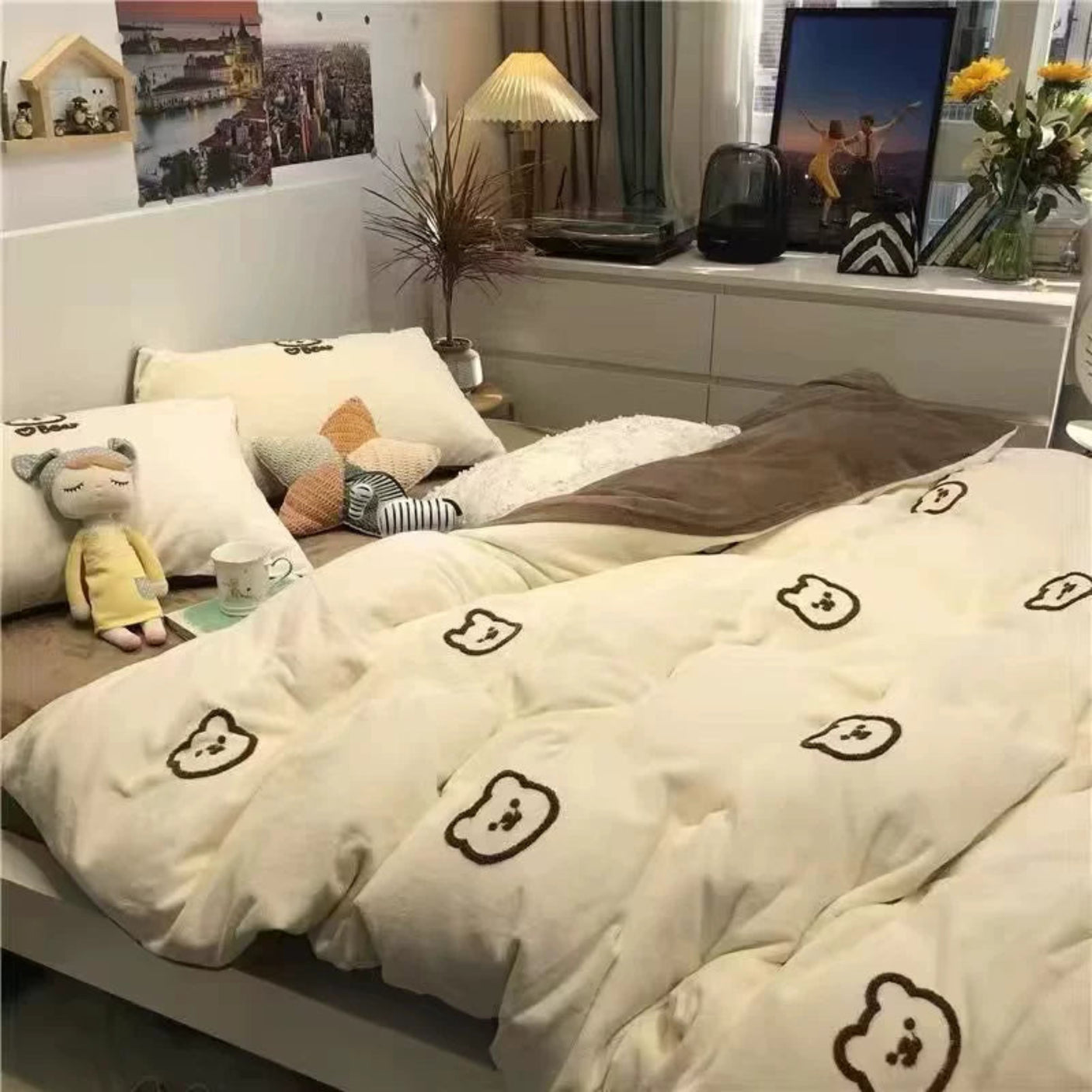Bedroom with white bedding featuring bear patterns, decorative pillows, and a lamp.