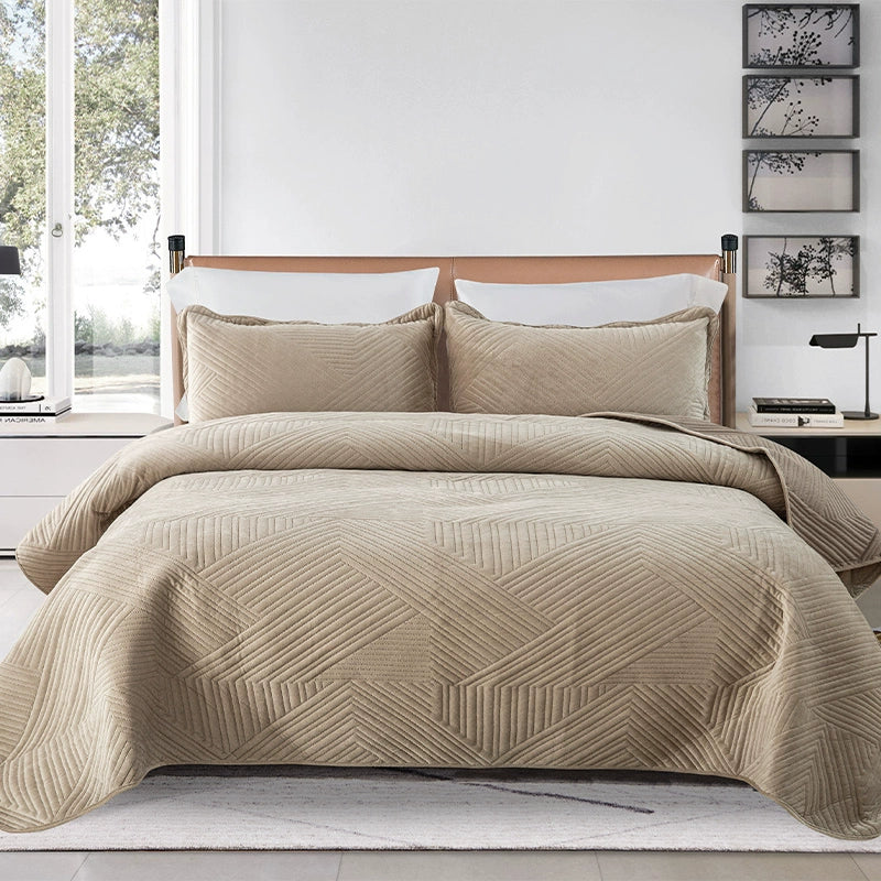 Beige quilted coverlet on a bed with matching pillows in a bedroom setting.
