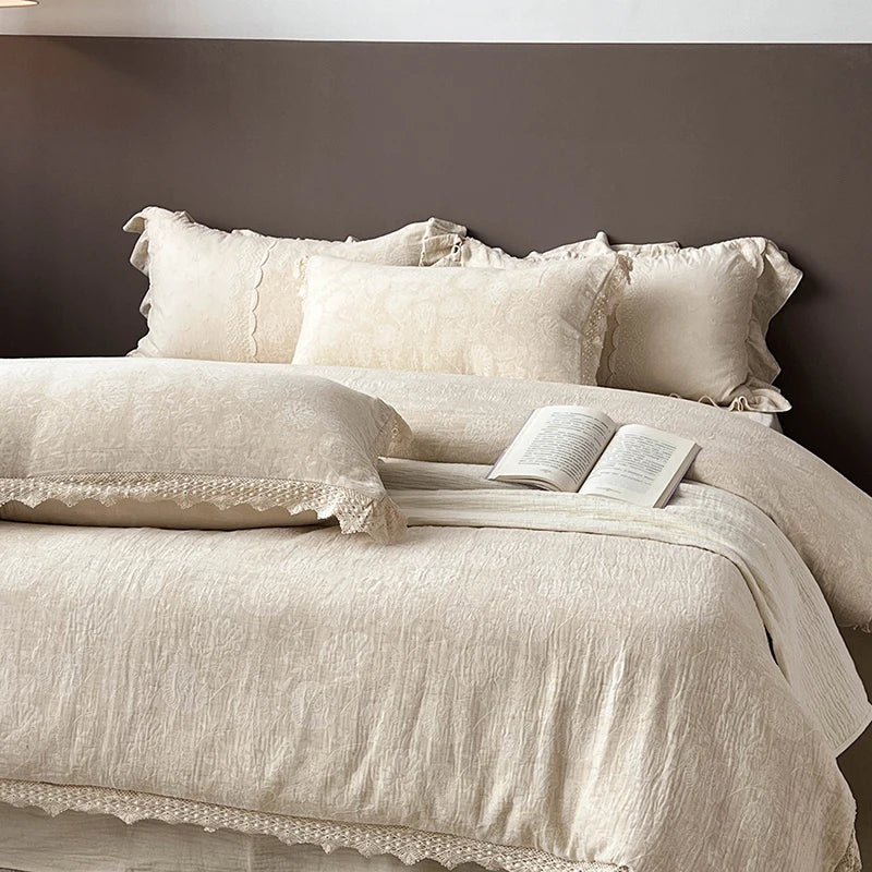 Beige textured bedspread with lace details on a bed against a dark wall.