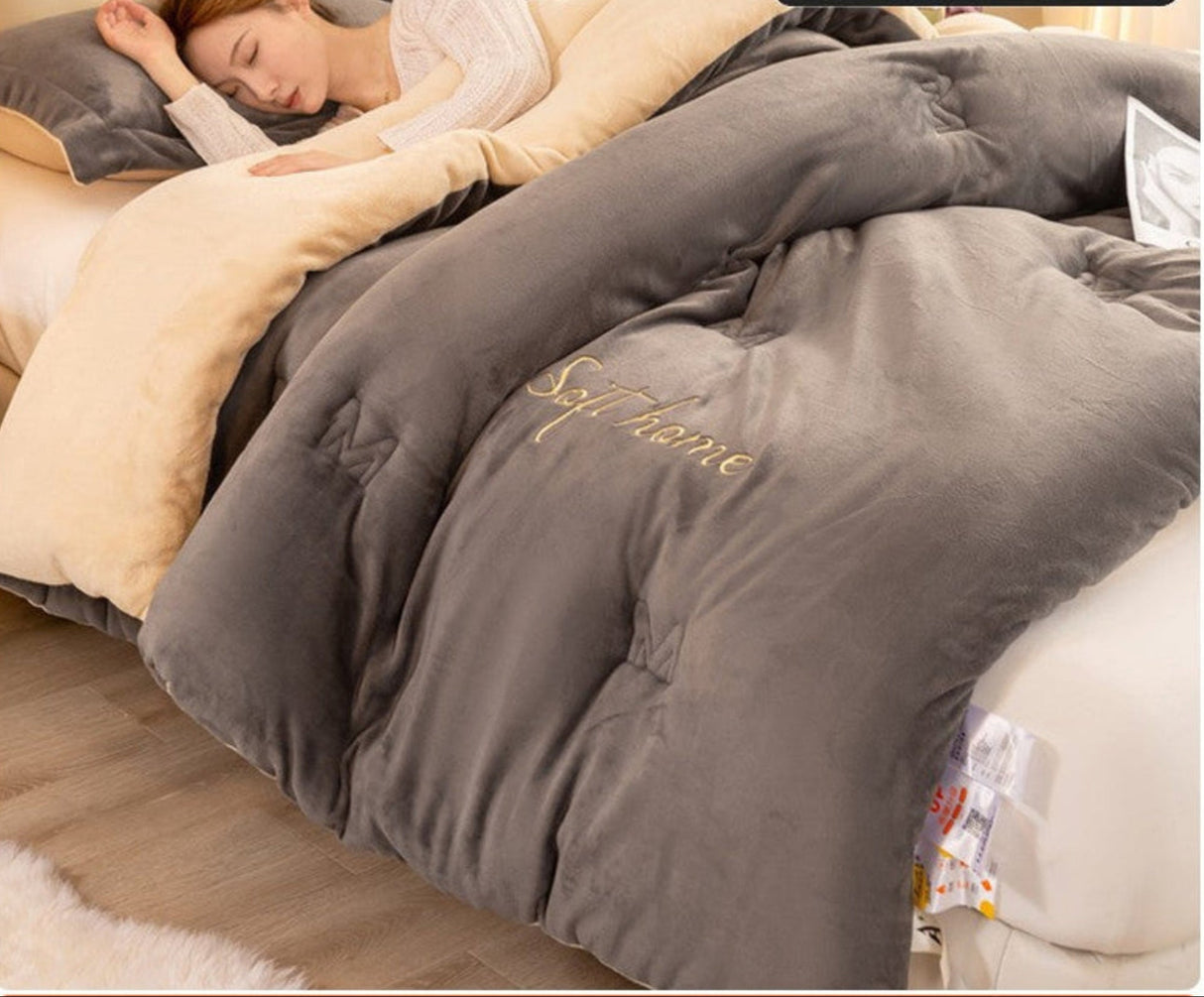 Gray comforter with 'Soft Home' branding on a bed, with a person partially visible.