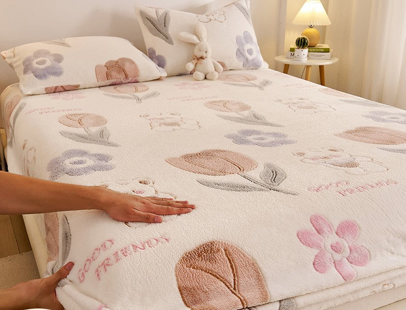 Floral and animal patterned bedspread on a bed with a hand touching it, in a bedroom setting.