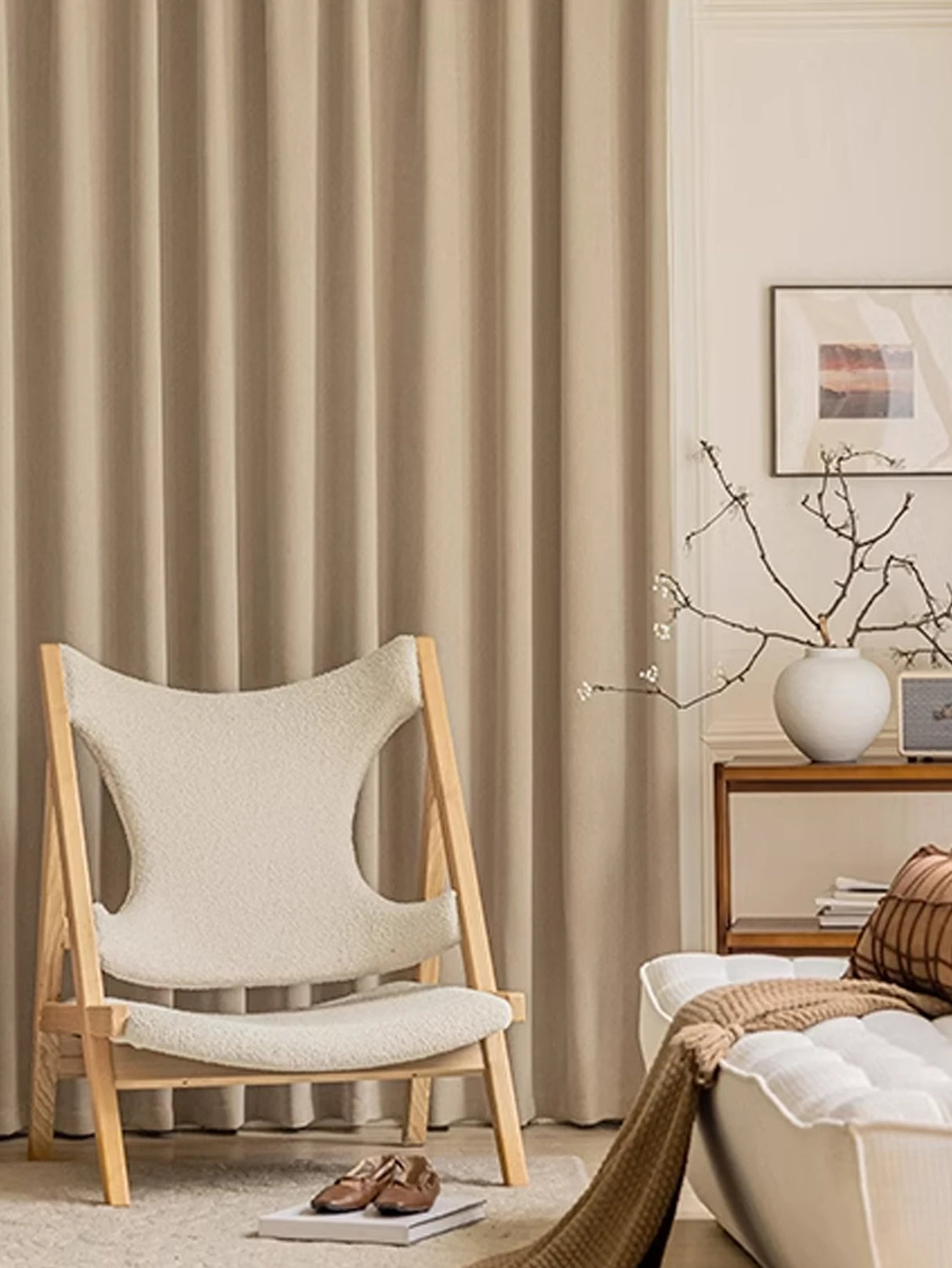 Beige chair in a living room with curtains and a side table.
