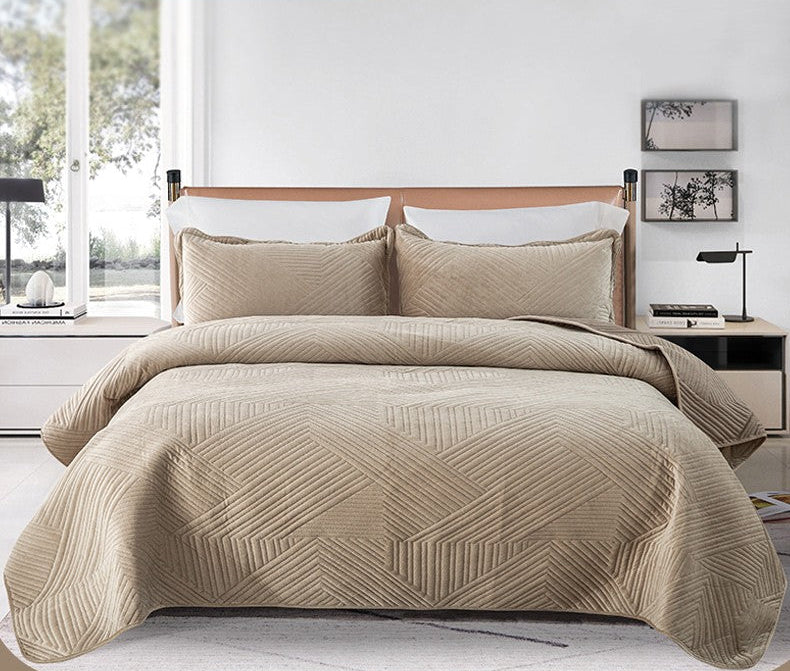 Beige quilted bed cover on a bed with a minimalistic room background.