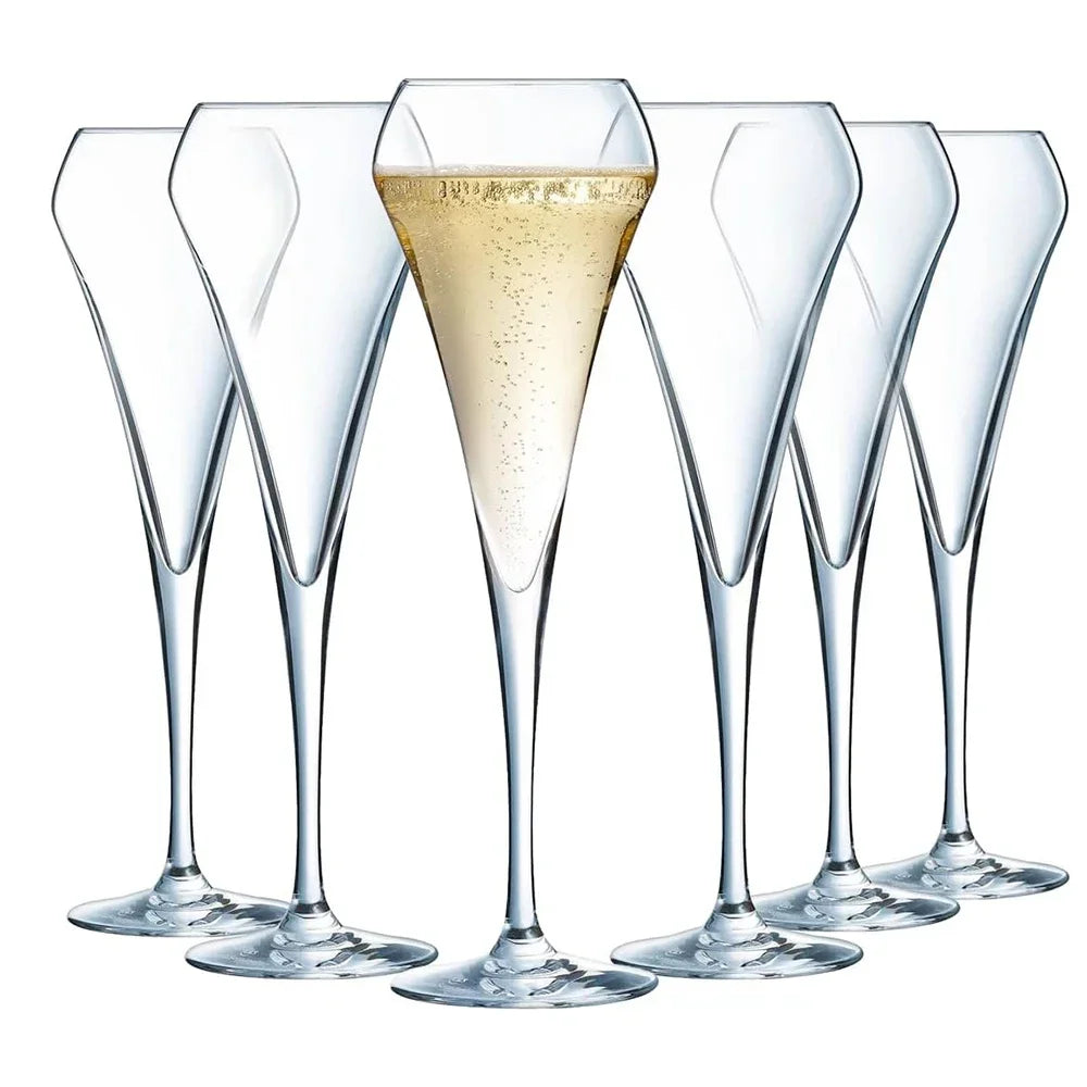 Set of six clear champagne flutes with one filled with champagne on a white background