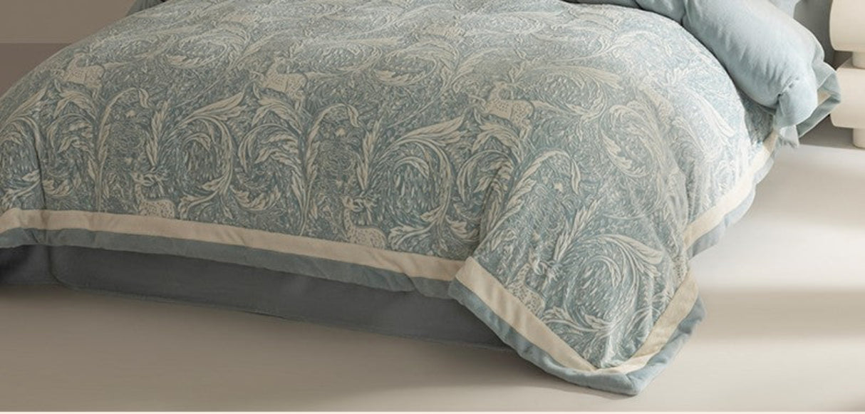 Teal patterned comforter on a bed with beige bedding.