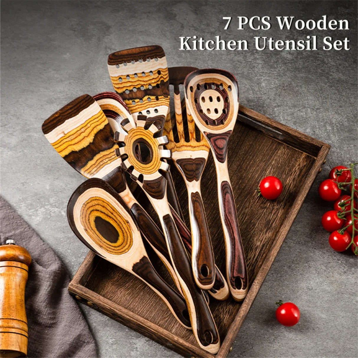 7-piece wooden kitchen utensil set on a tray with tomatoes and a towel in the background.
