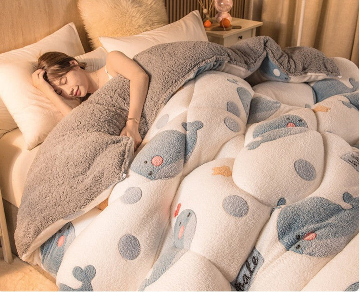 Person sleeping under a cartoon whale-patterned comforter in a bedroom.