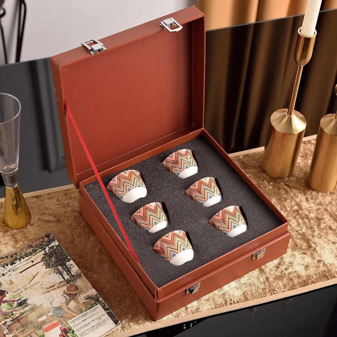 Set of decorative stones in a brown leather box on a table with a candle and glassware.