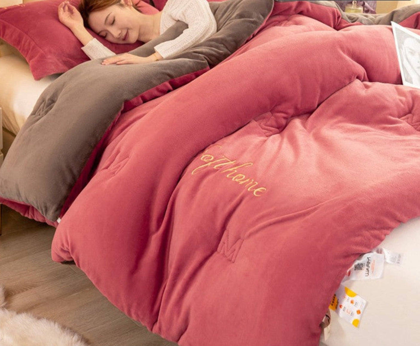 Pink comforter with text on a bed, showing texture and use scenarios.