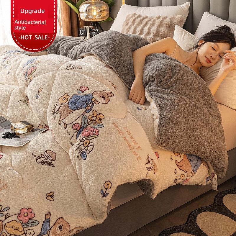 Woman lying on a bed with a decorative blanket featuring cartoon characters, in a cozy bedroom setting.