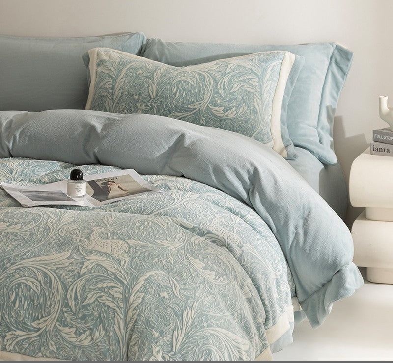 Teal patterned bedding set on a bed with pillows and a nightstand.