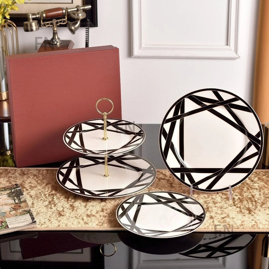 Set of black and white patterned plates on a decorative stand with a white wall background.