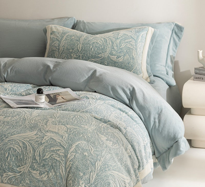 Patterned light blue bedding set on a bed with pillows and a nightstand.