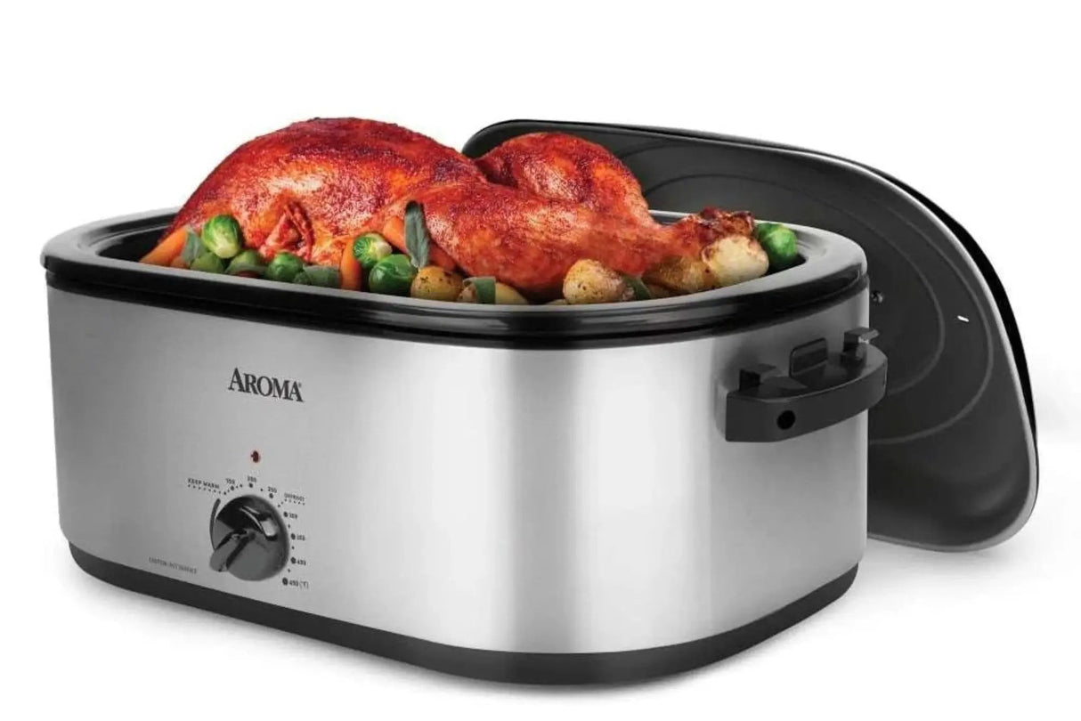 Stainless steel roaster with roasted chicken and vegetables on a white background