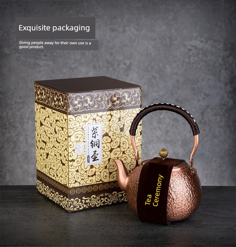 Copper teapot with 'Tea Ceremony' text next to an ornate packaging box on a dark background.