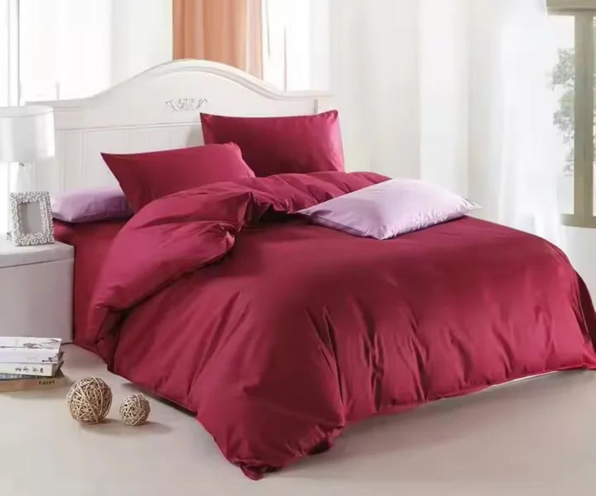 Maroon bedding set on a bed with white headboard and light-colored floor.