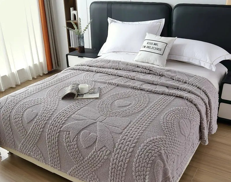 Gray textured blanket on a bed with pillows in a bedroom setting